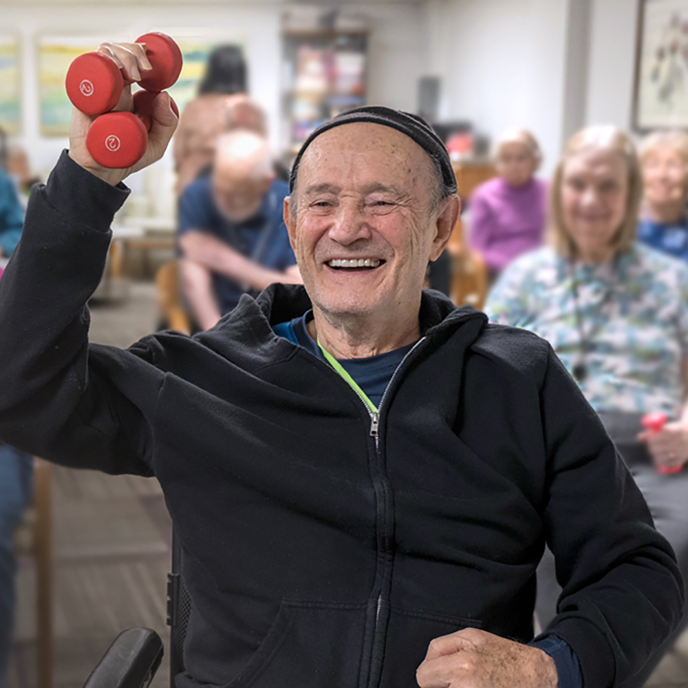 Resident participating in a group wellness class and lifting hand weights at Atrium